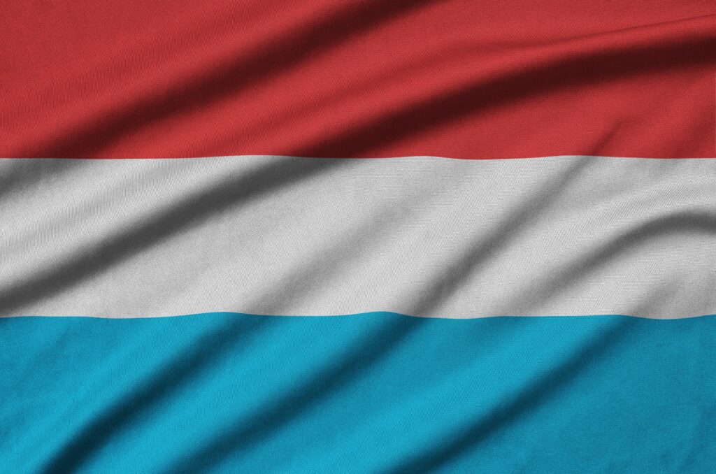 Luxembourg flag is depicted on a sports cloth fabric with many folds. Sport team waving banner